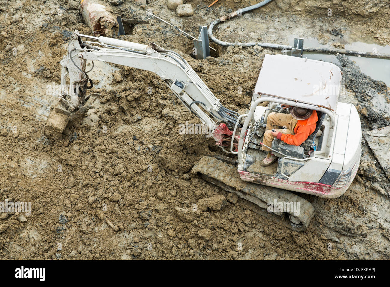 Caucasian worker operating digger at construction site Stock Photo