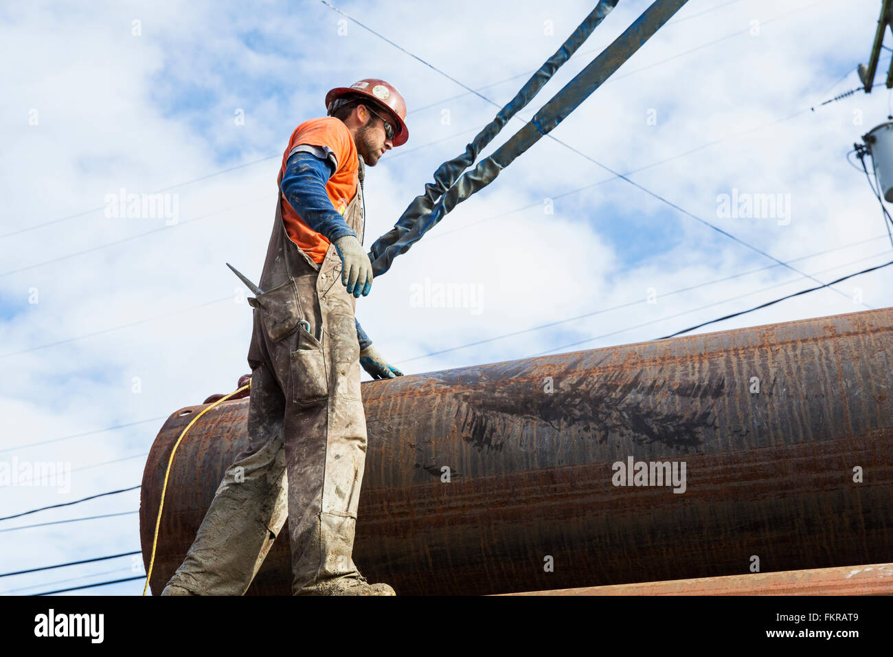 Caucasian worker hauling pipe at construction site Stock Photo
