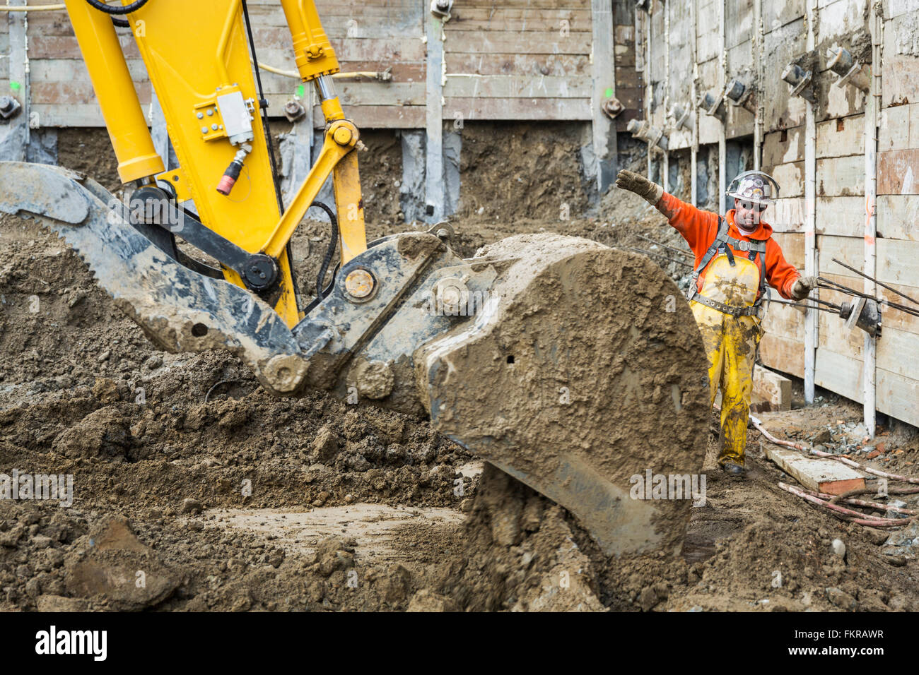 Caucasian worker directing digger at construction site Stock Photo