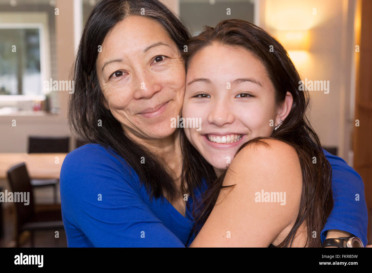 Mother and daughter hugging indoors Stock Photo