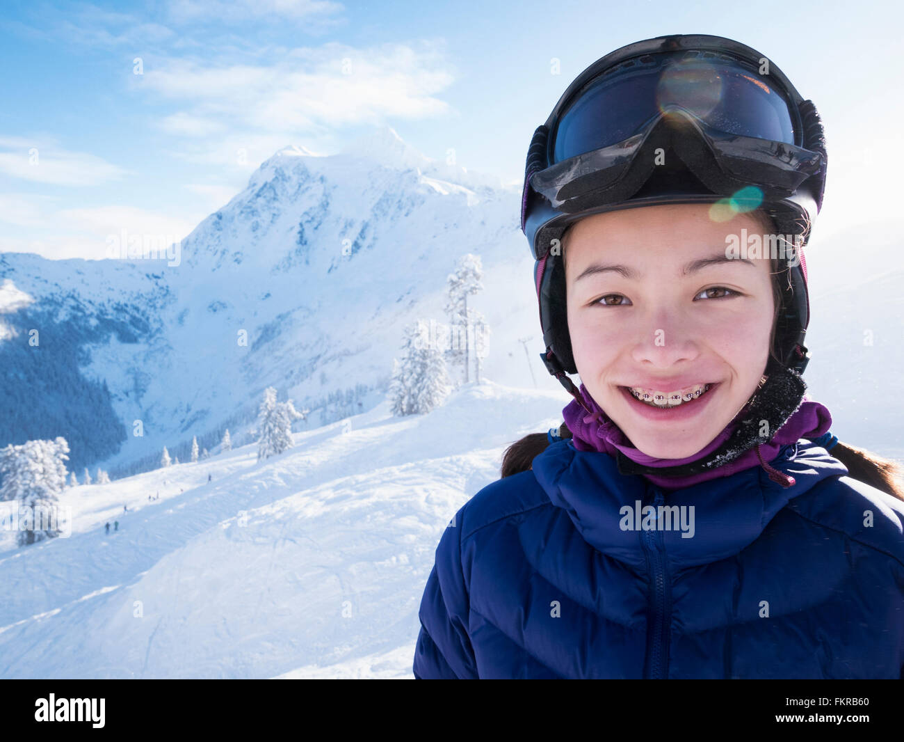 Mixed race girl smiling on snowy mountain Stock Photo