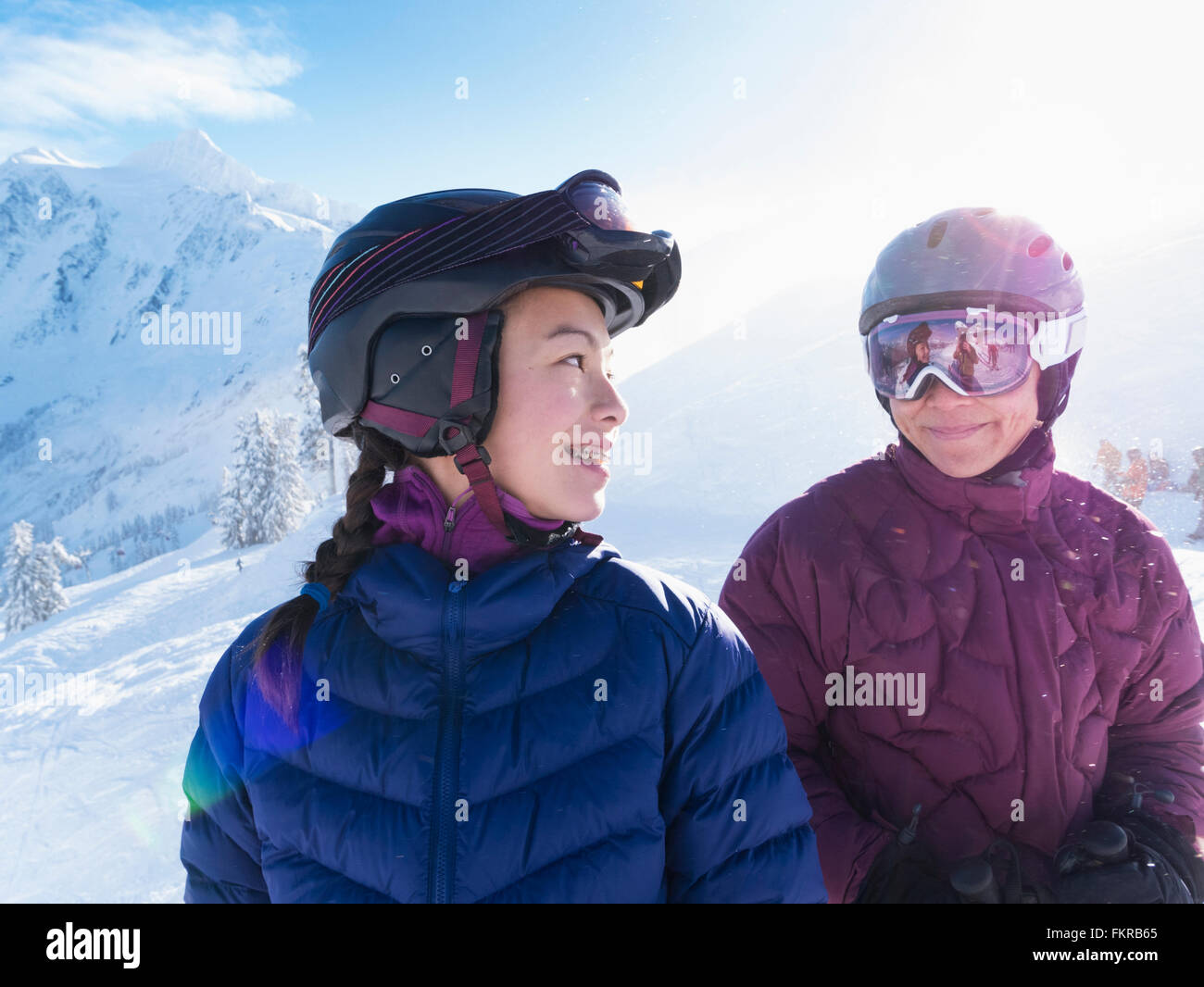 Mother and daughter wearing ski gear on snowy mountain Stock Photo