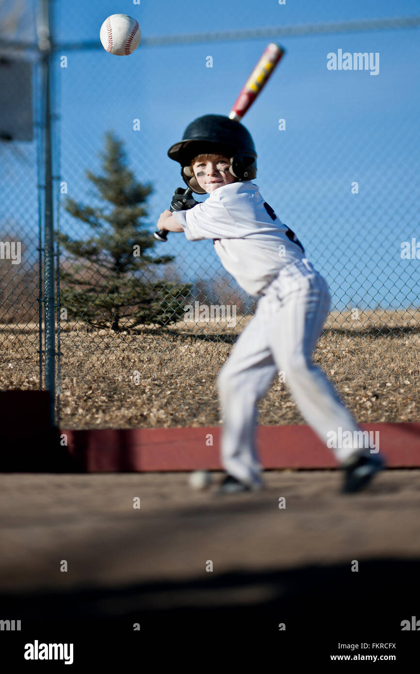 Caucasian boy hitting baseball on field Stock Photo Alamy