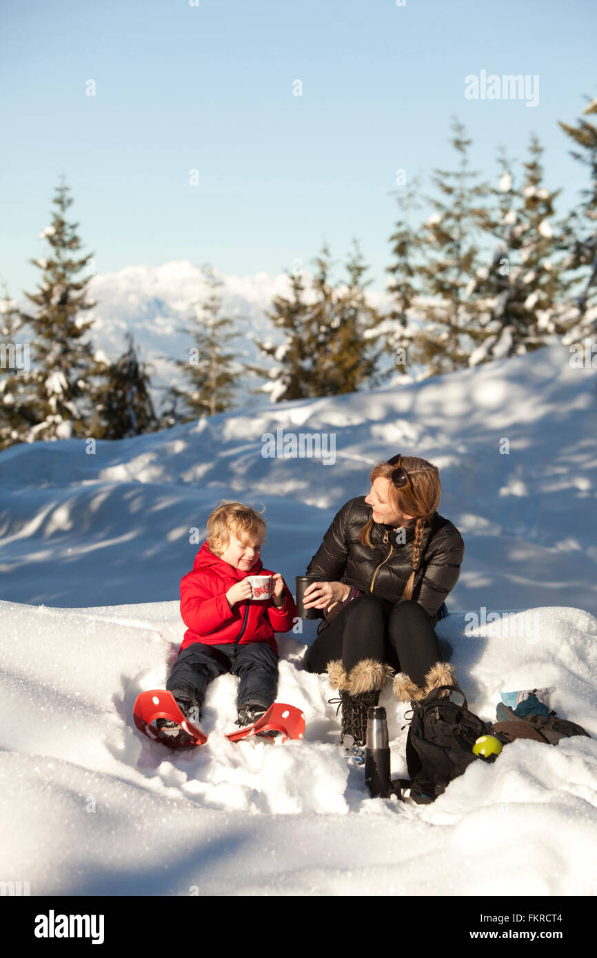 Caucasian mother and son drinking hot cocoa in snow Stock Photo