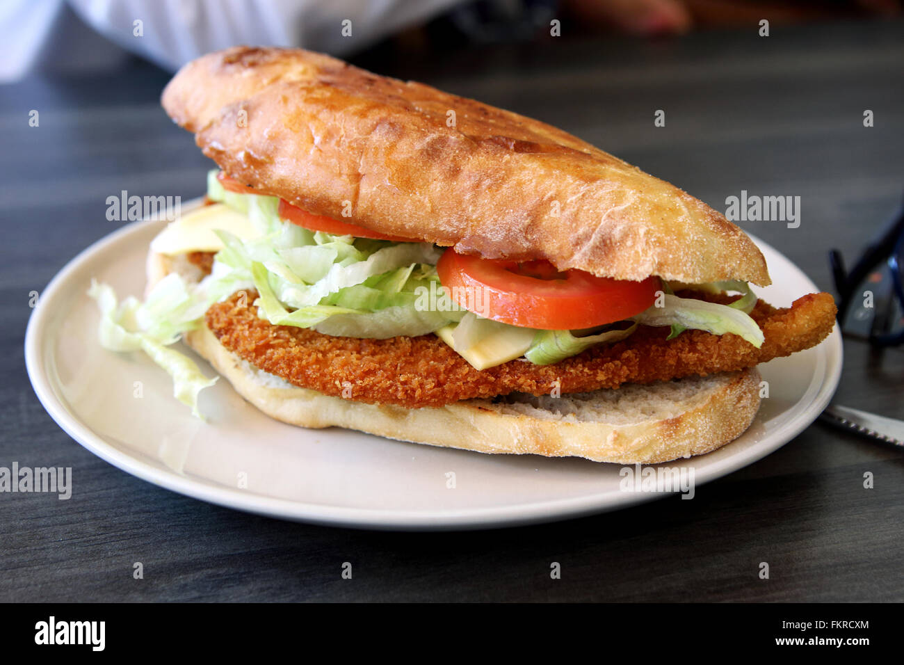 Chicken Schnitzel burger on a white plate against wooden background