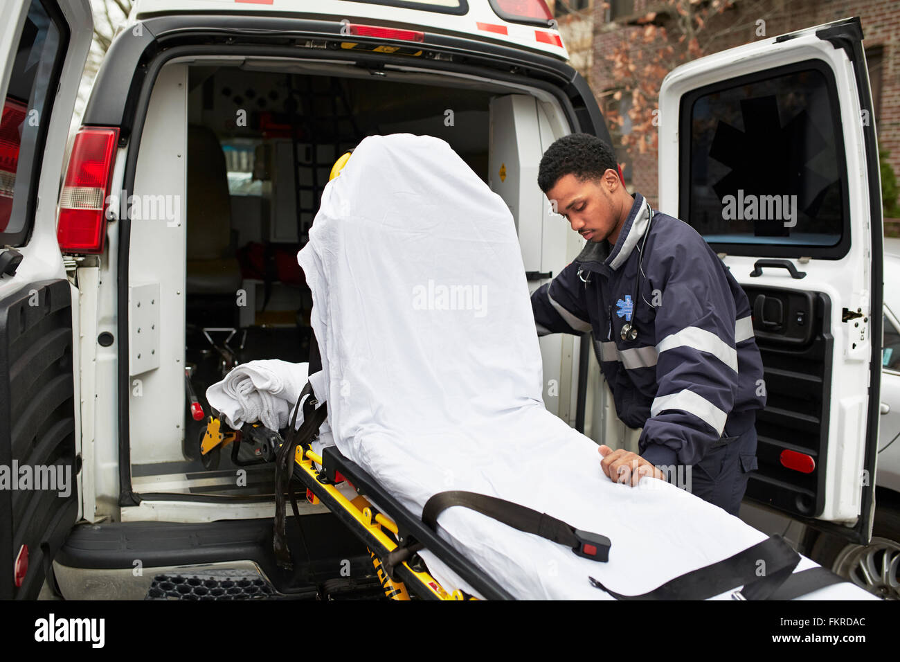 Mixed race paramedic rolling gurney from ambulance Stock Photo Alamy