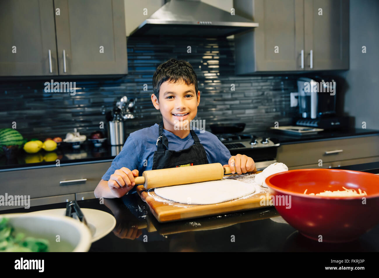 Mixed race boy rolling dough in kitchen Stock Photo