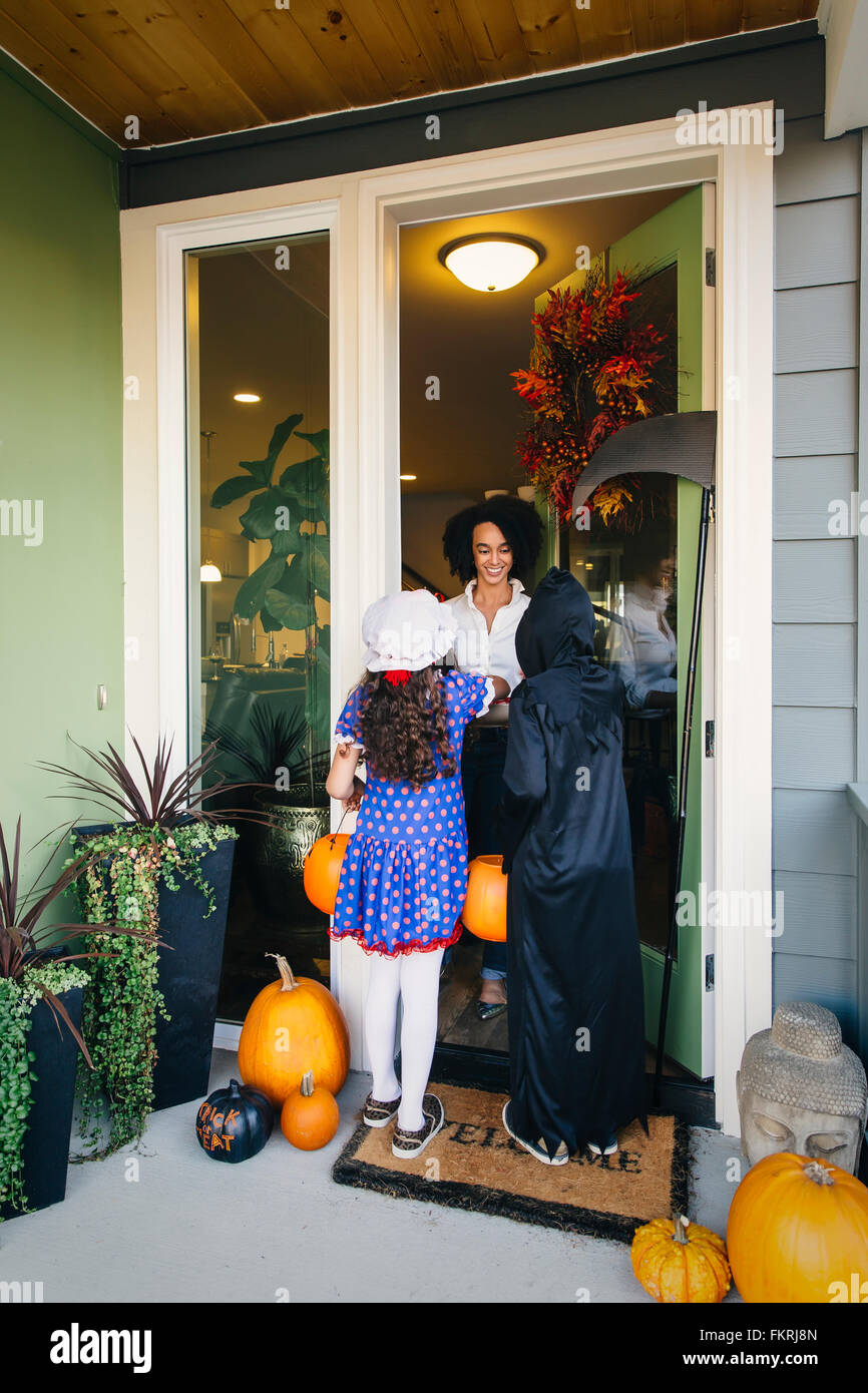 Woman receiving trick-or-treaters on Halloween Stock Photo