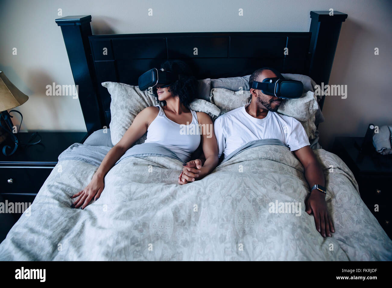 Couple using virtual reality goggles in bed Stock Photo