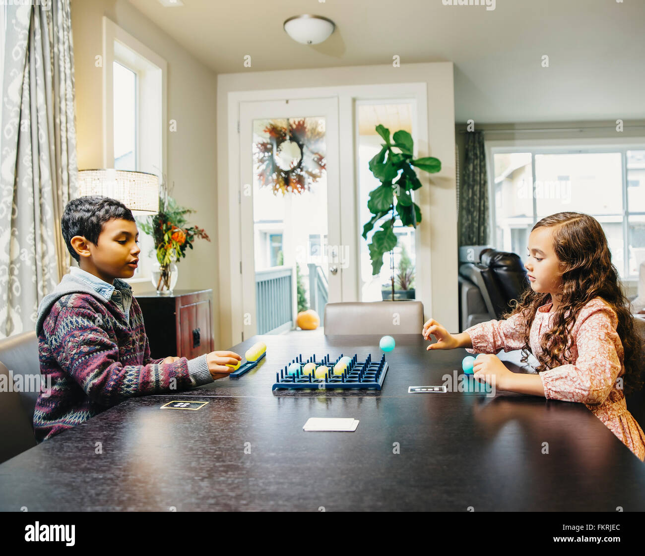 Mixed race siblings playing board game Stock Photo