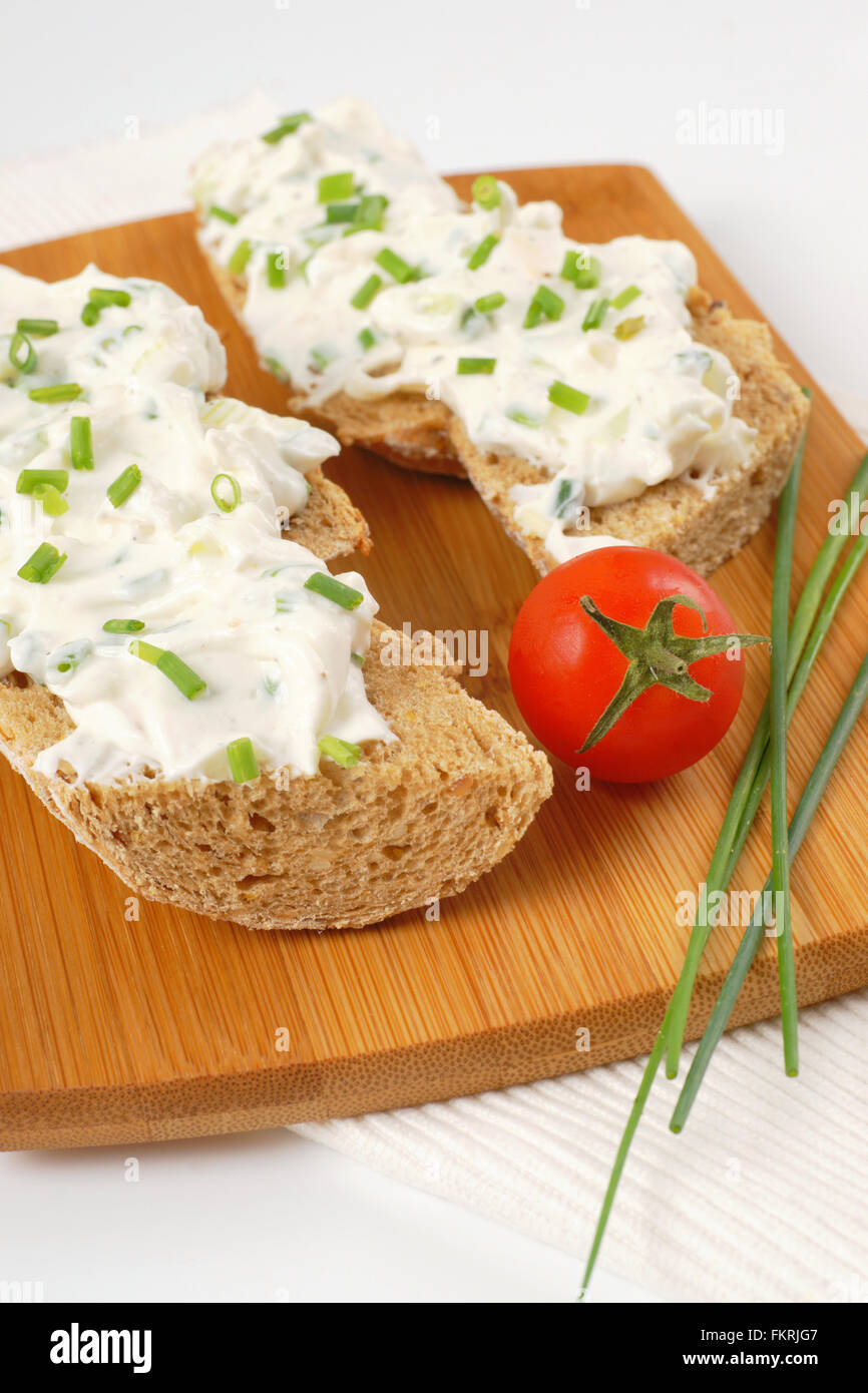open faced sandwich with chives spread on wooden cutting board Stock