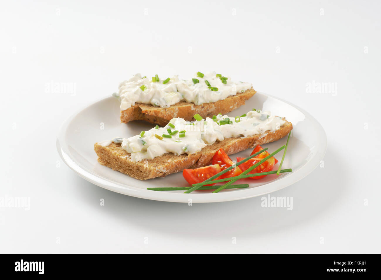 open faced sandwich with chives spread on white plate Stock Photo Alamy