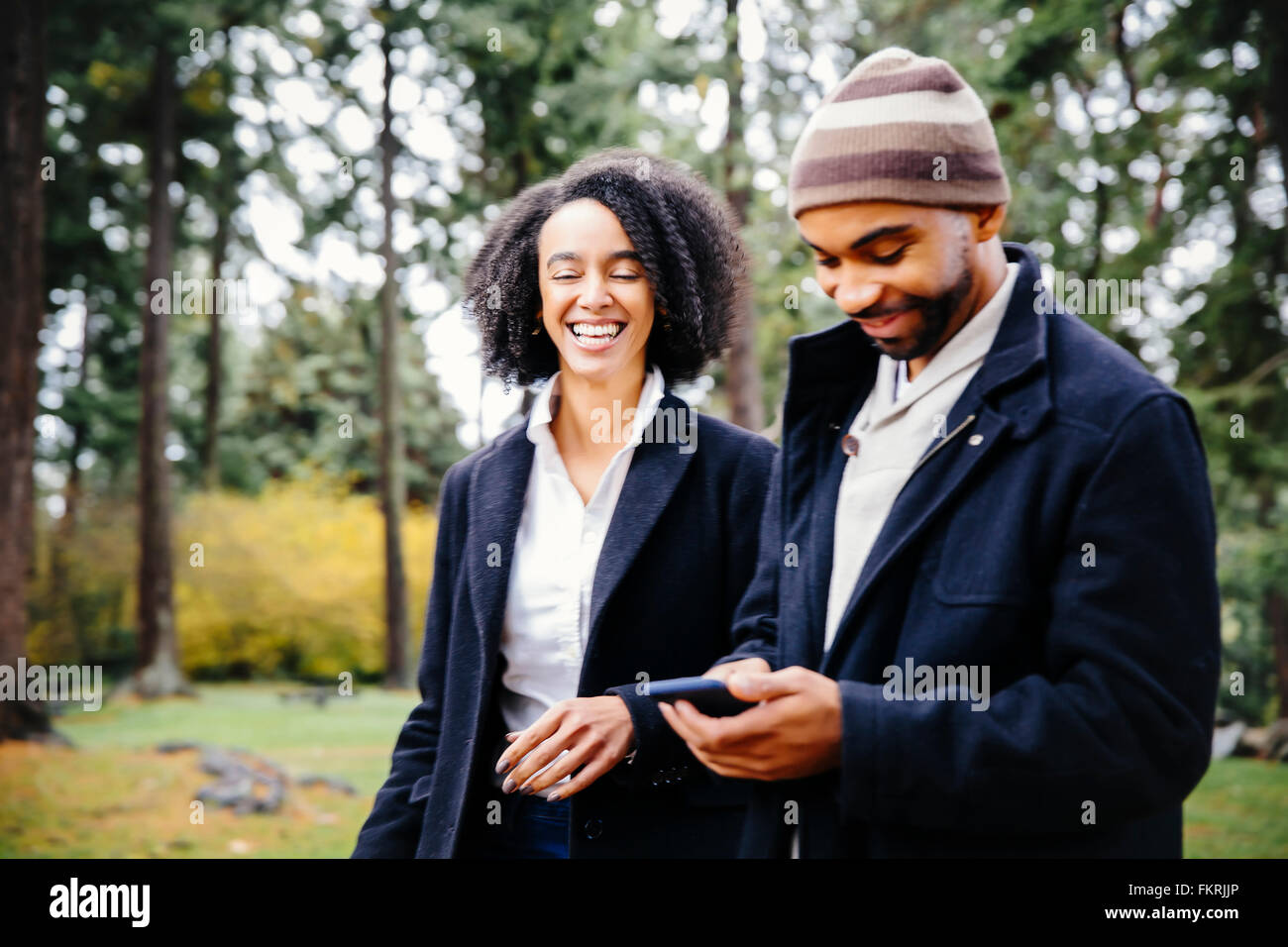 Couple using cell phone in park Stock Photo