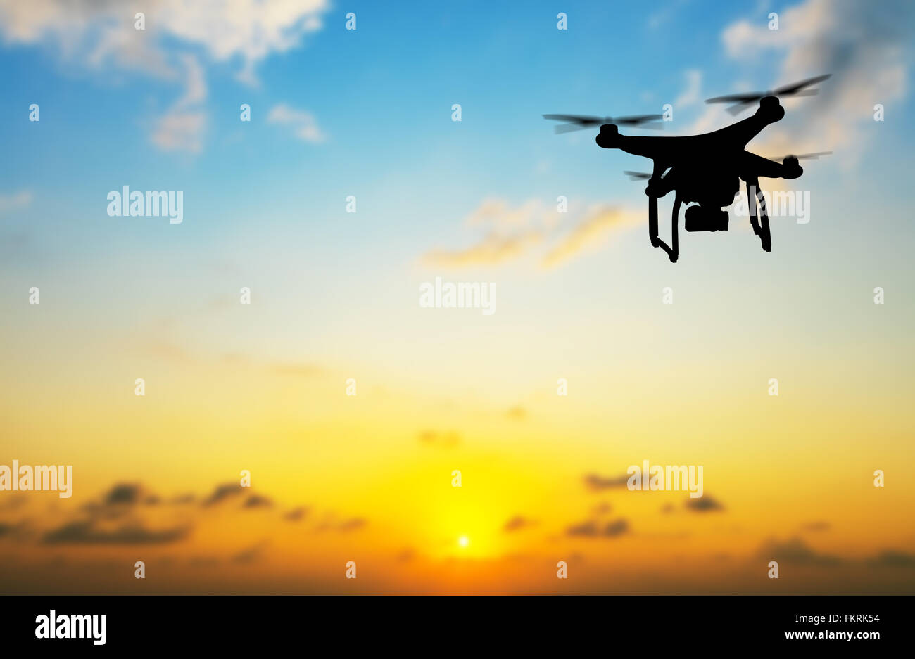 Flying silhouette of drone against sunset Stock Photo