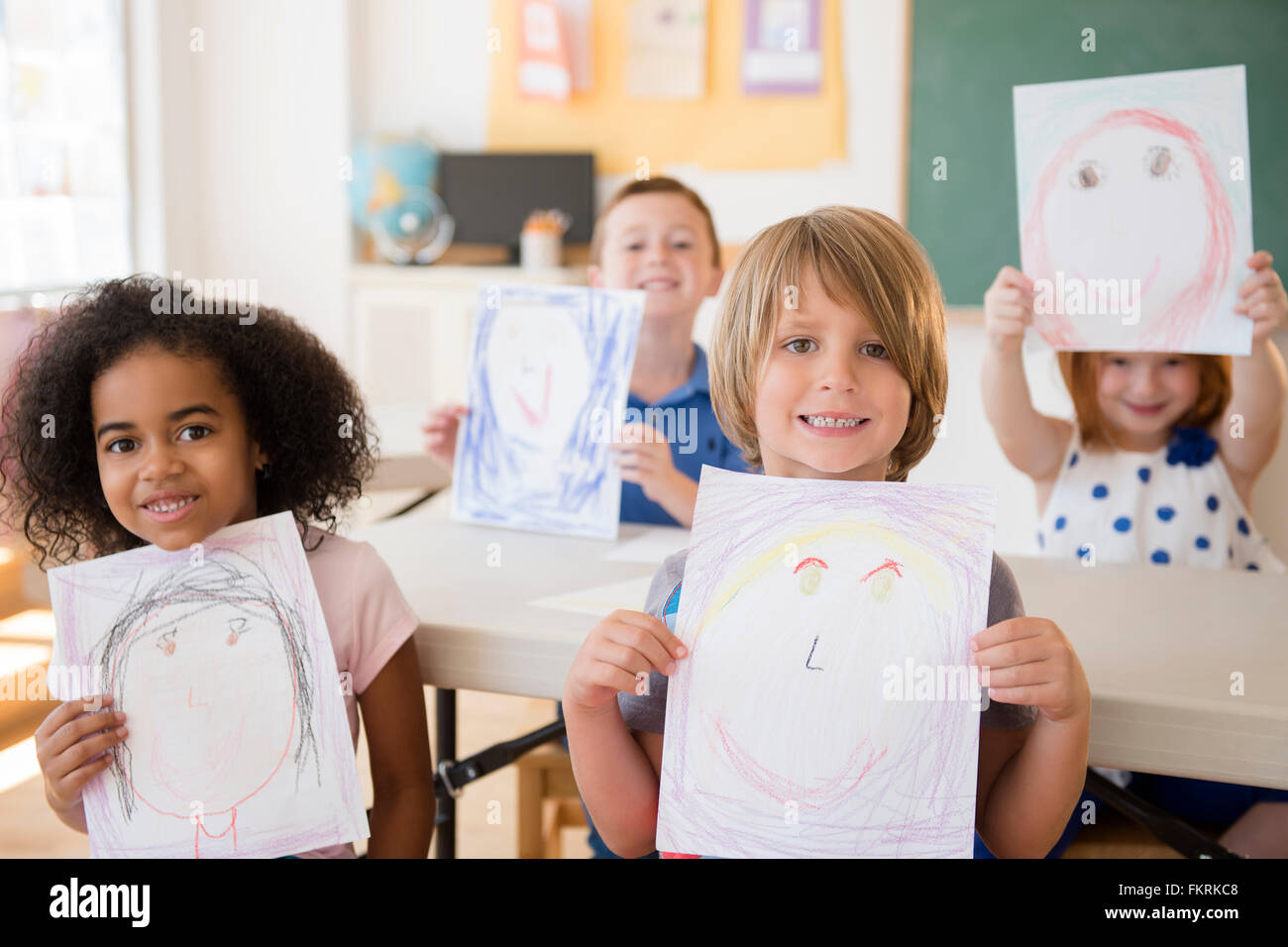 Students showing drawings in classroom Stock Photo