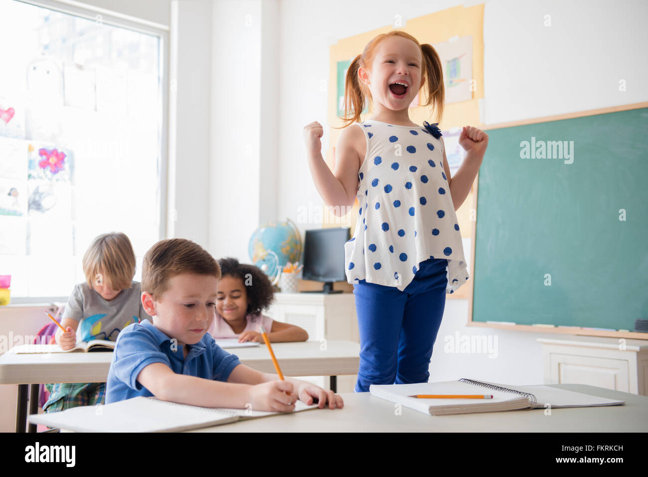 Student shouting at desk in classroom Stock Photo