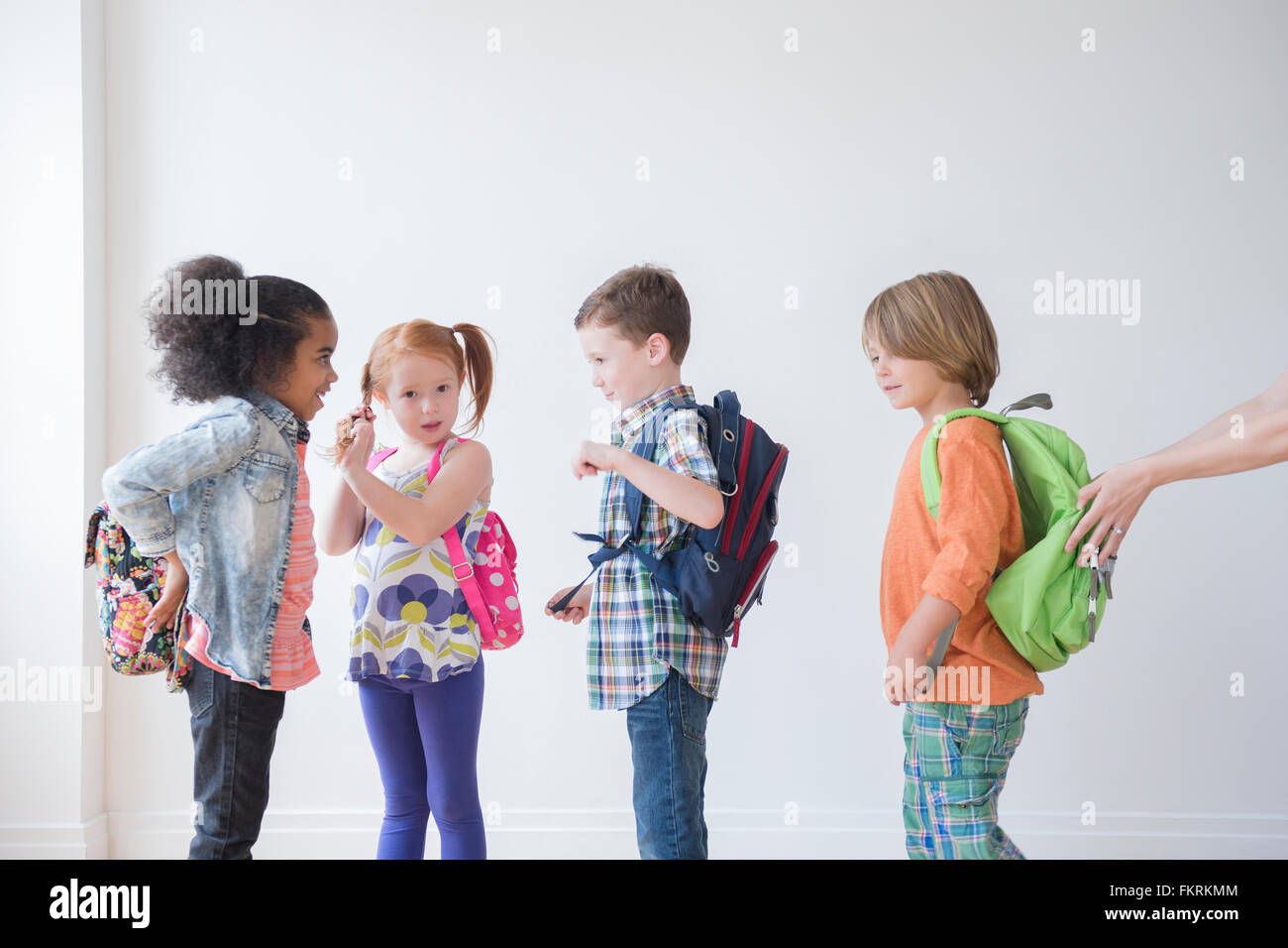 Students wearing backpacks in classroom Stock Photo