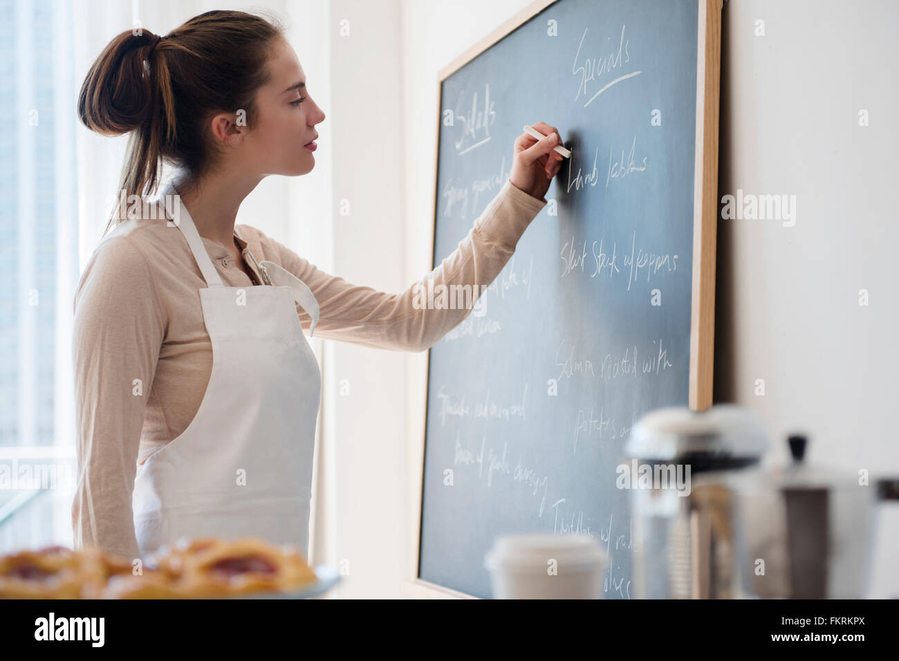 Native American woman writing on specials board in cafe Stock Photo