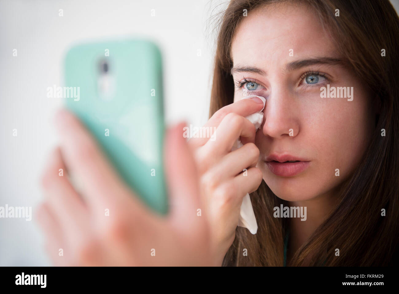 Native American woman with cell phone wiping away tears Stock Photo