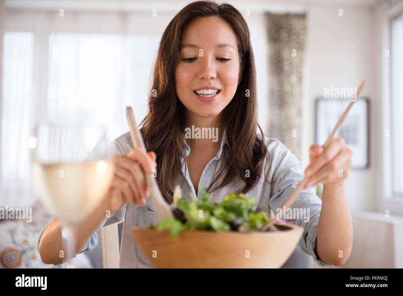 Mixed race woman tossing salad Stock Photo