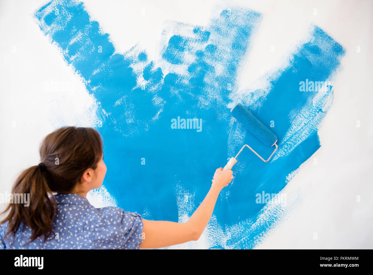 Mixed race woman painting wall Stock Photo