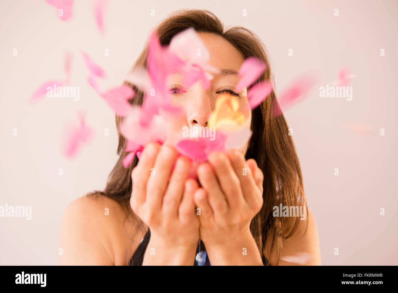 Mixed race woman blowing confetti Stock Photo