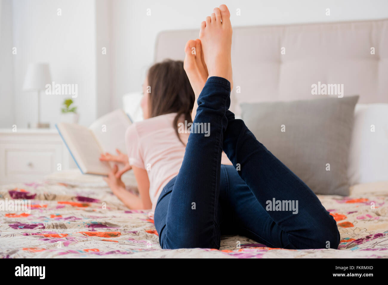 Mixed race woman reading book on bed Stock Photo