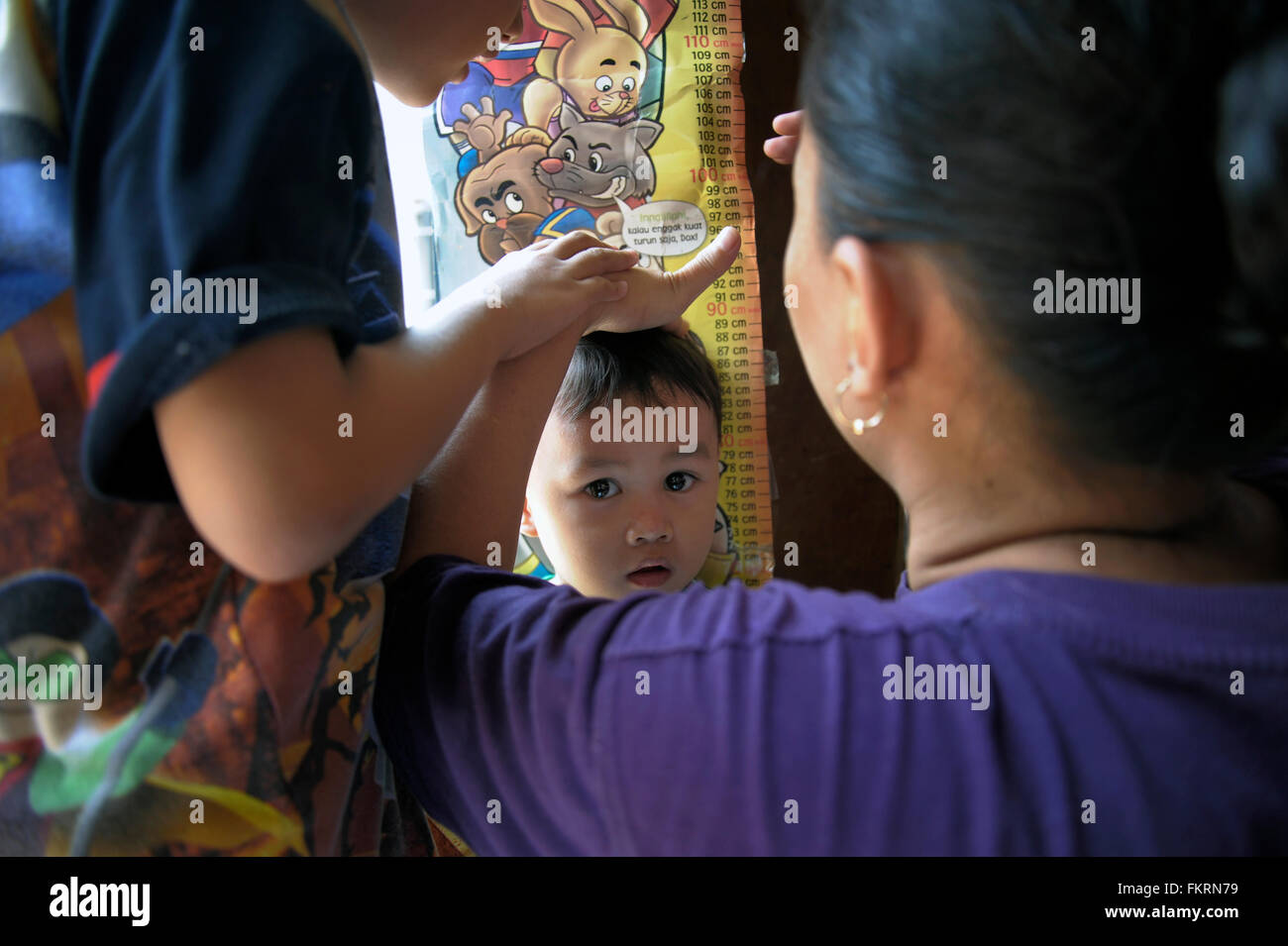 A woman measuring a boy's height. After being declared polio-free by World Health Organization officials in 2014, Indonesia is observing National Polio Immunization Week by vowing to inoculate millions of children. The expanded mass immunization drive against polio and measles began simultaneously. The polio immunization drive is targeting children aged 9 to 59 months old, and that for measles infants nine month to 59 month old. (Photo by Agung Samosir / Pacific Press) Stock Photo