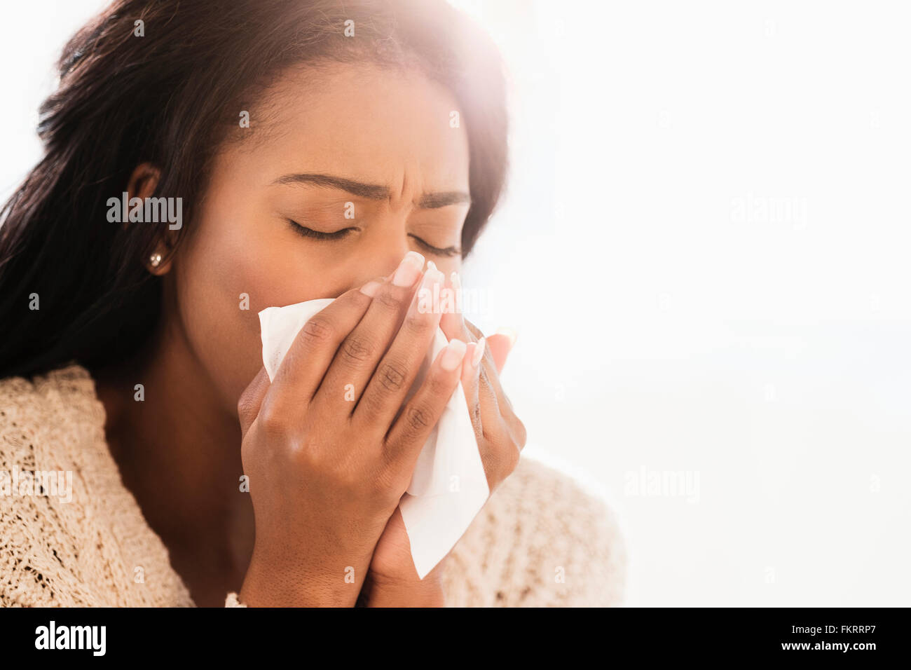 Mixed race woman blowing her nose Stock Photo