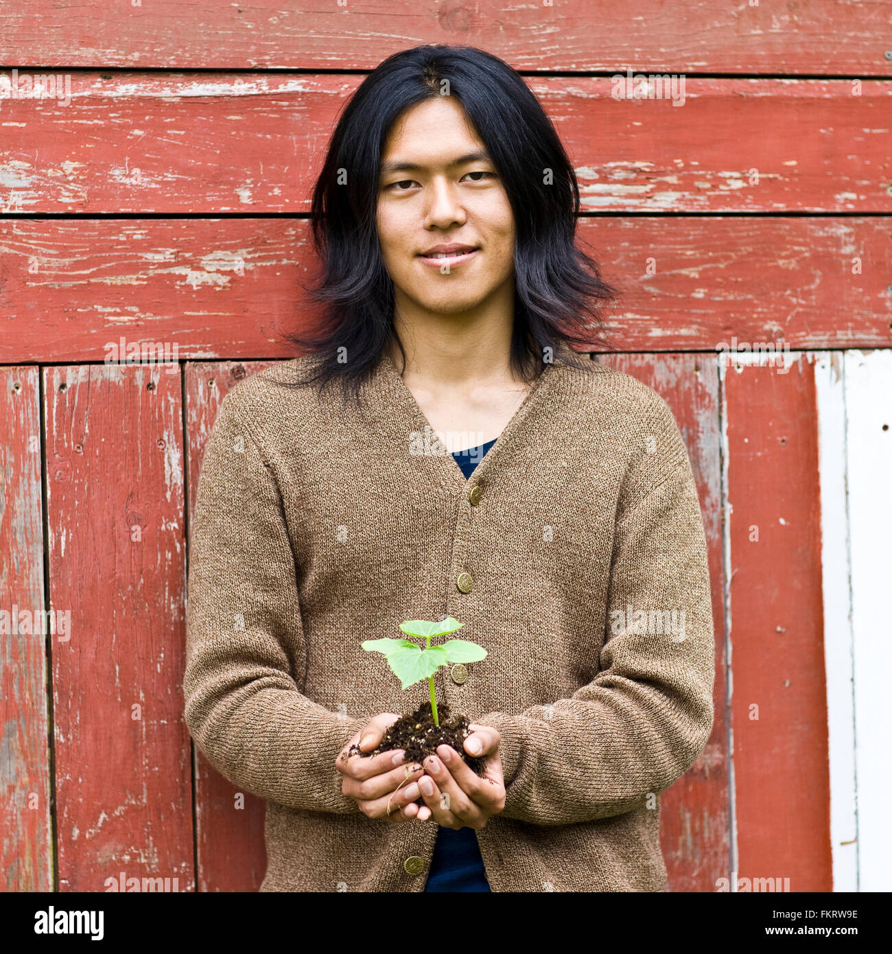Japanese man holding potted plant outdoors Stock Photo