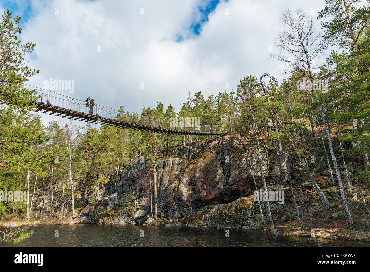 Trekker crossing a hanging bridge in Repovesi National Park, Finland. Stock Photo