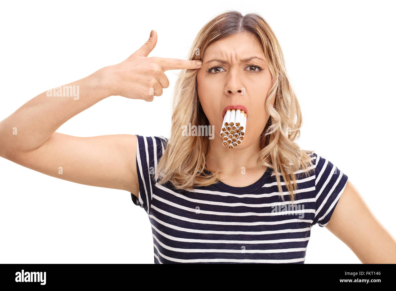 Blond woman with a bunch of cigarettes in her mouth holding a hand gun on her head isolated on white background Stock Photo