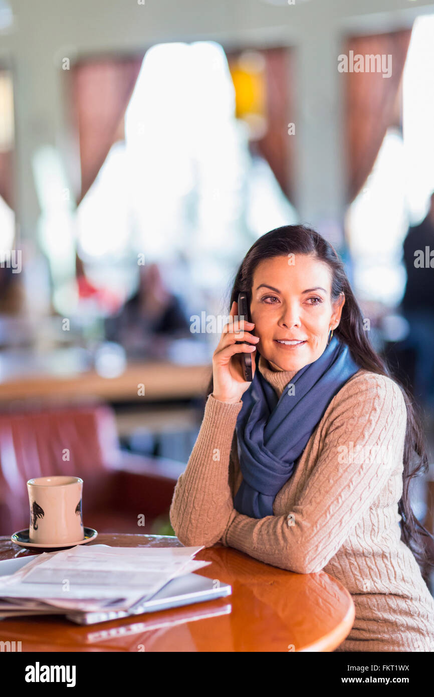 Hispanic woman talking on cell phone in cafe Stock Photo - Alamy