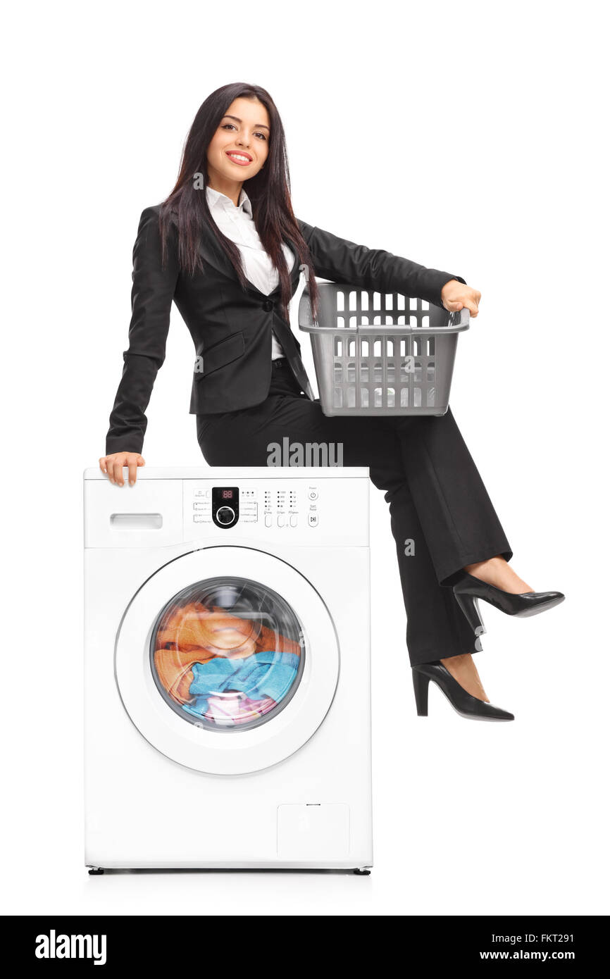 Vertical shot of a young businesswoman waiting for the laundry seated on a washing machine isolated on white background Stock Photo