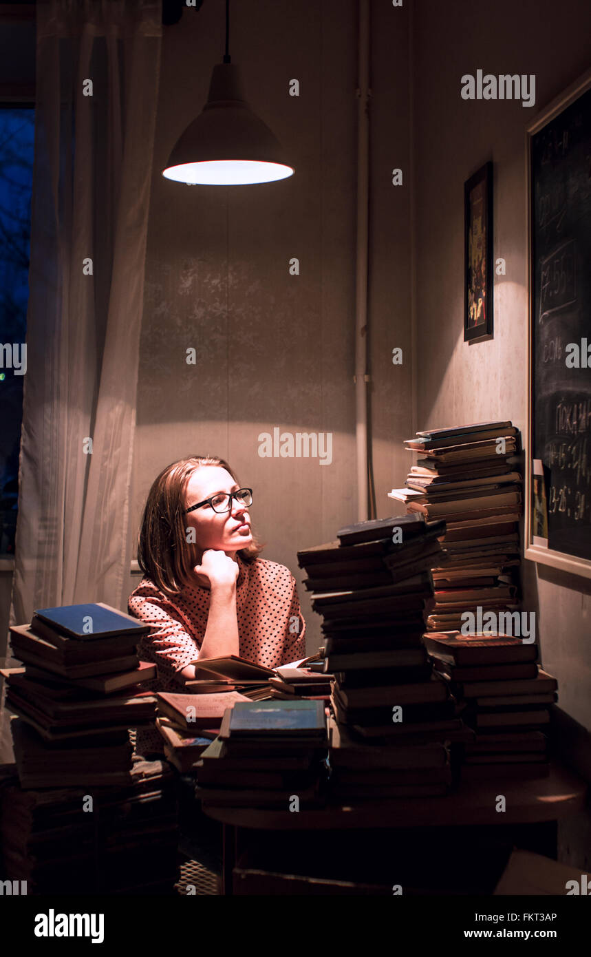 Caucasian woman sitting at stack of books Stock Photo