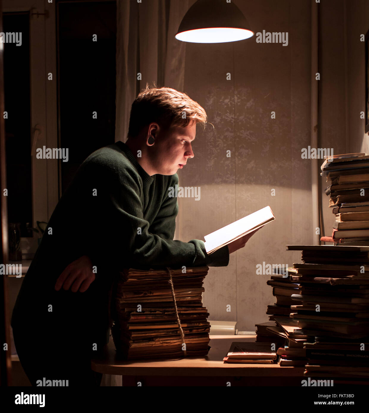 Caucasian man reading stack of books Stock Photo
