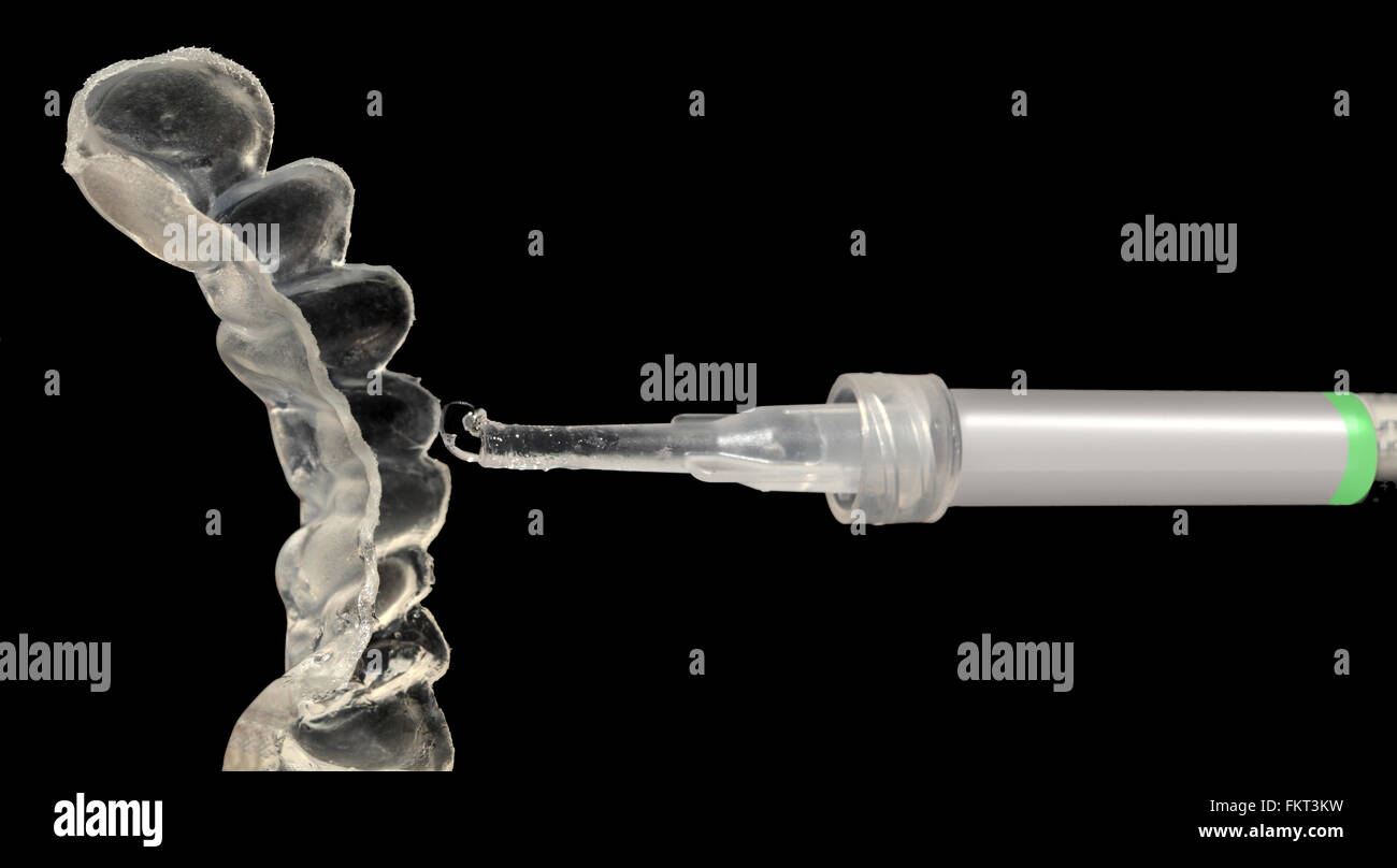 A tooth mold being filled with teeth whitening gel from a syringe