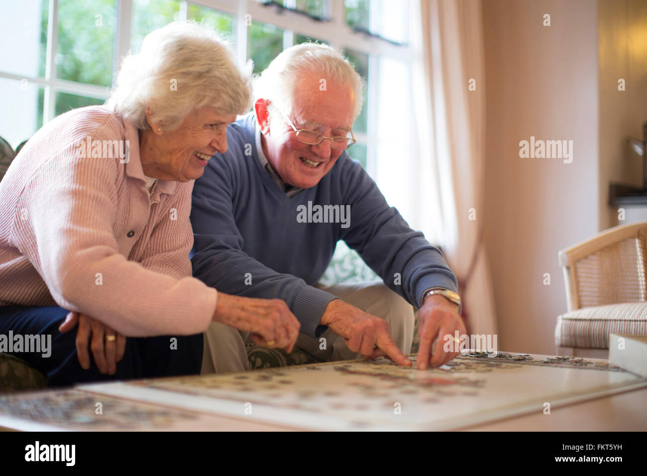 Older couple on sofa solving jigsaw puzzle Stock Photo