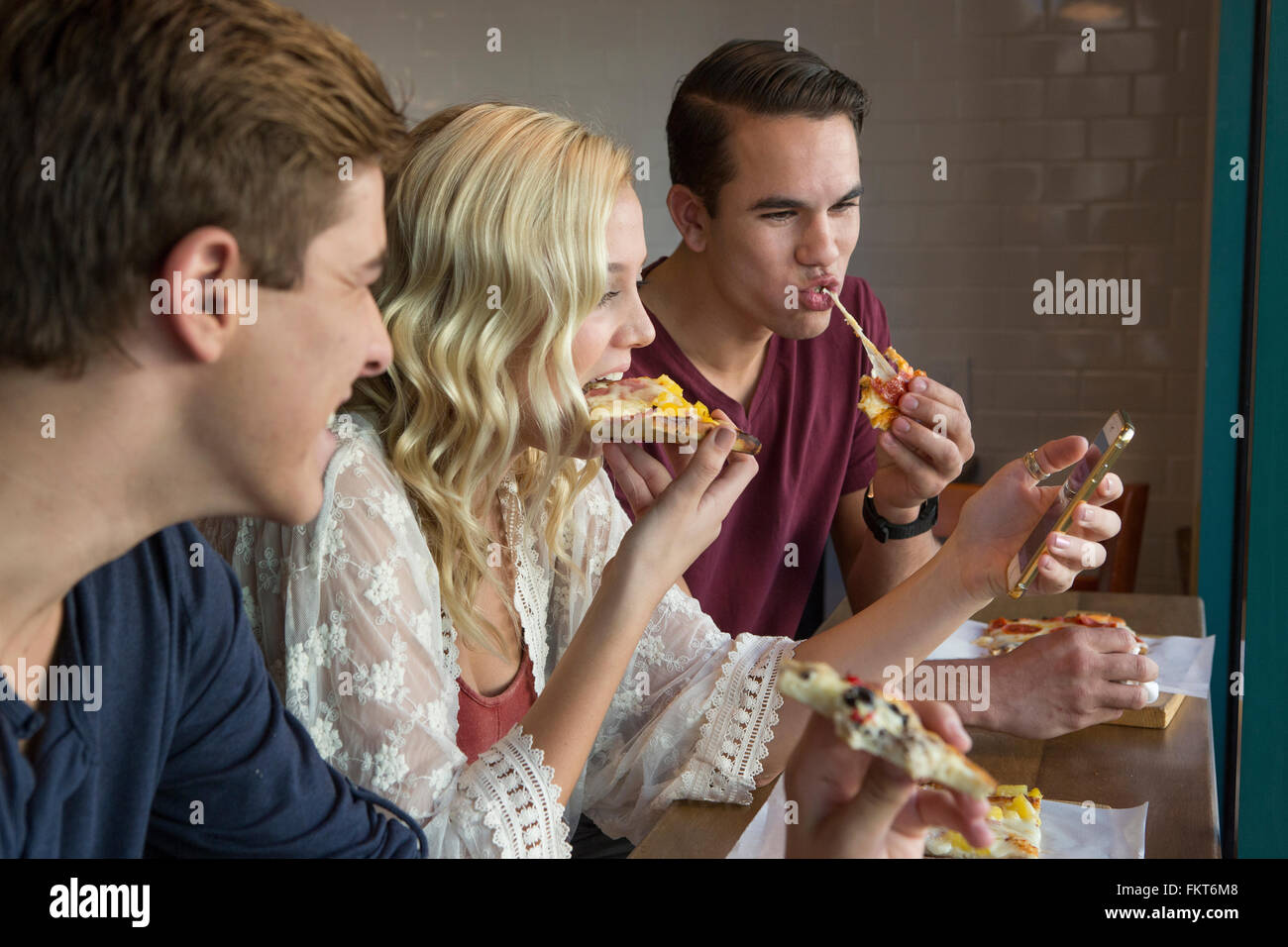 Caucasian friends eating pizza in cafe Stock Photo