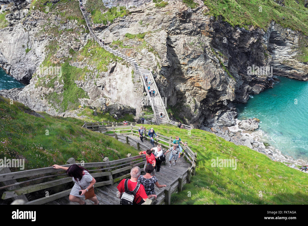 Tourists tackling the numerous steps built around the cliffs of Tintagel Castle, Tintagel, Cornwall, UK Stock Photo