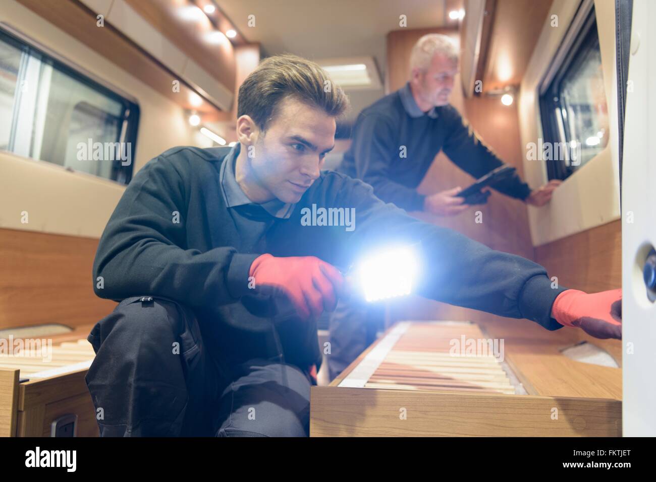 Workers inspecting vehicle on motorhome production line Stock Photo