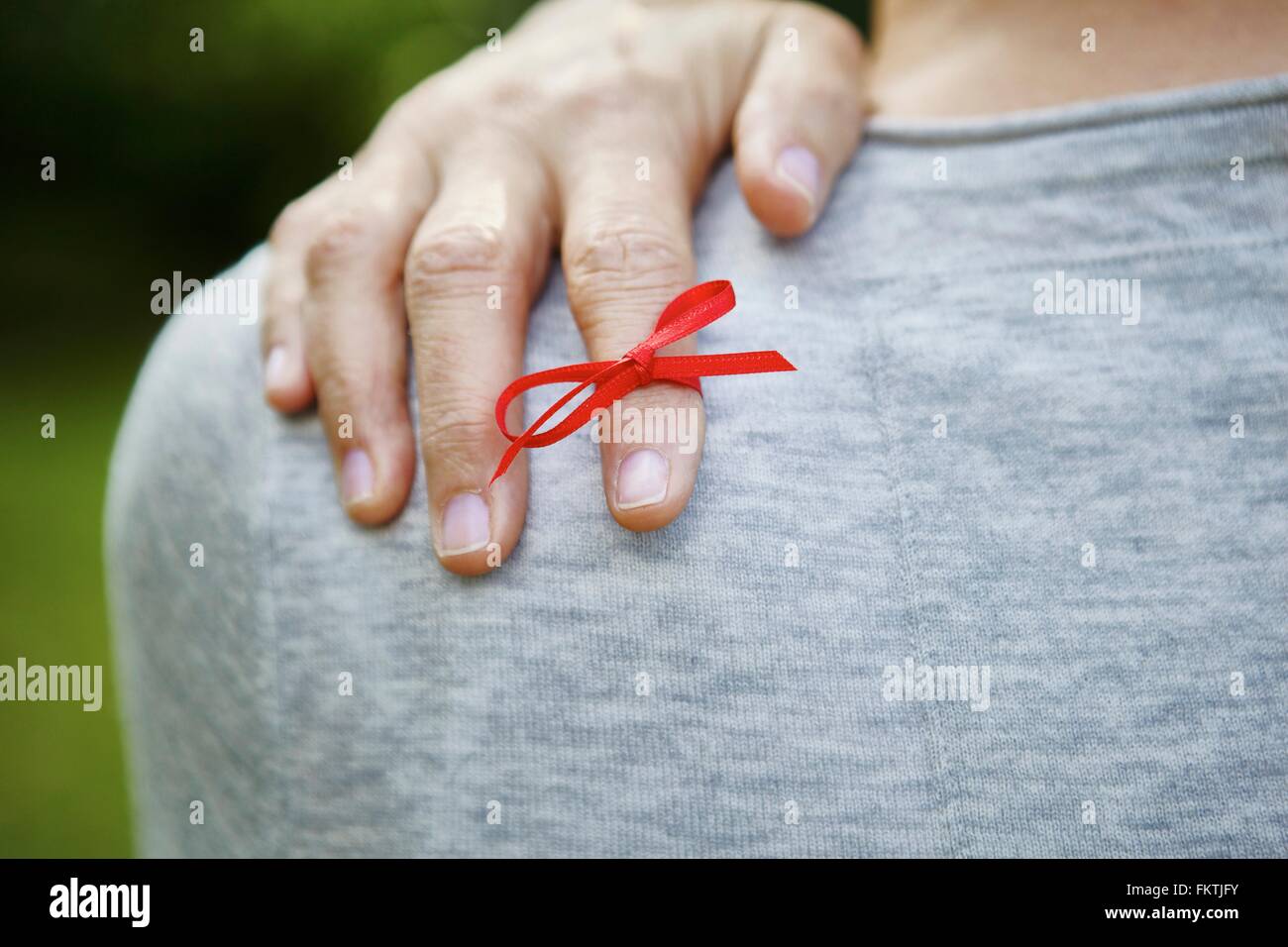 Red ribbon tied on index finger Stock Photo