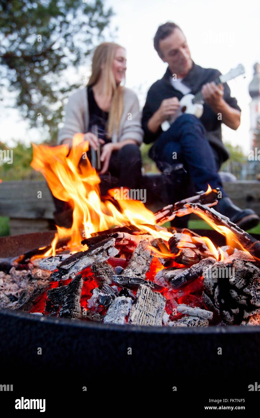 Flames in fire pit, couple in background Stock Photo