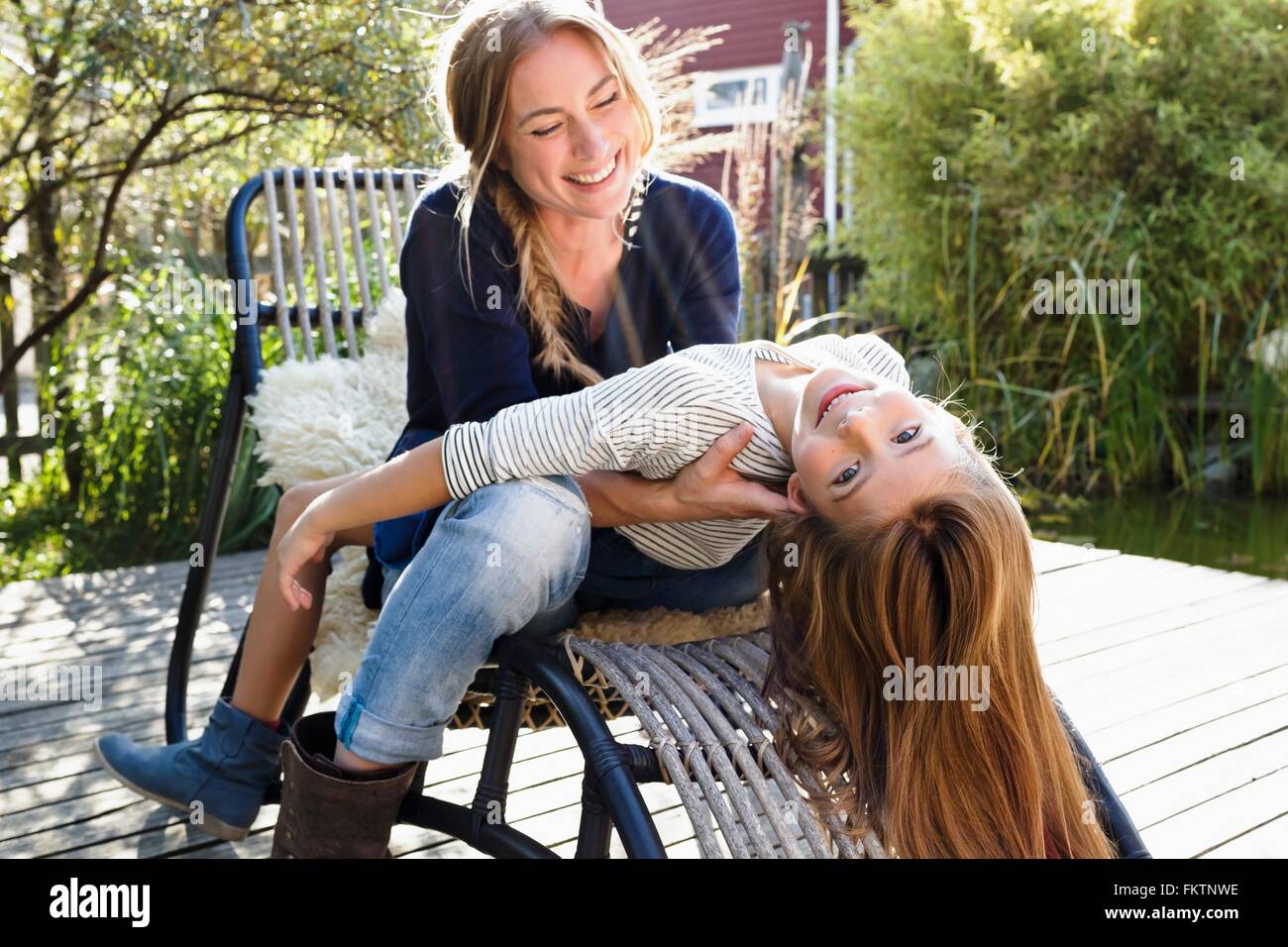 Girl sitting on mother's lap, leaning back Stock Photo