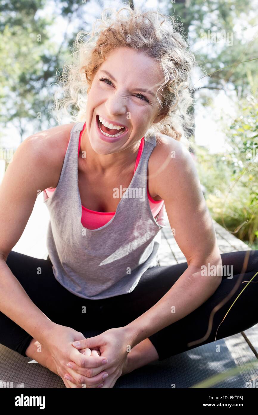 Young woman in sports clothes sitting on floor, laughing Stock Photo