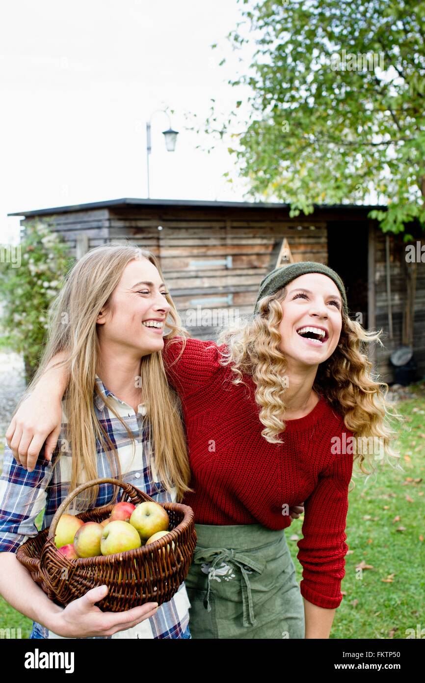 Two women in garden with basket   apples, laughing Stock Photo
