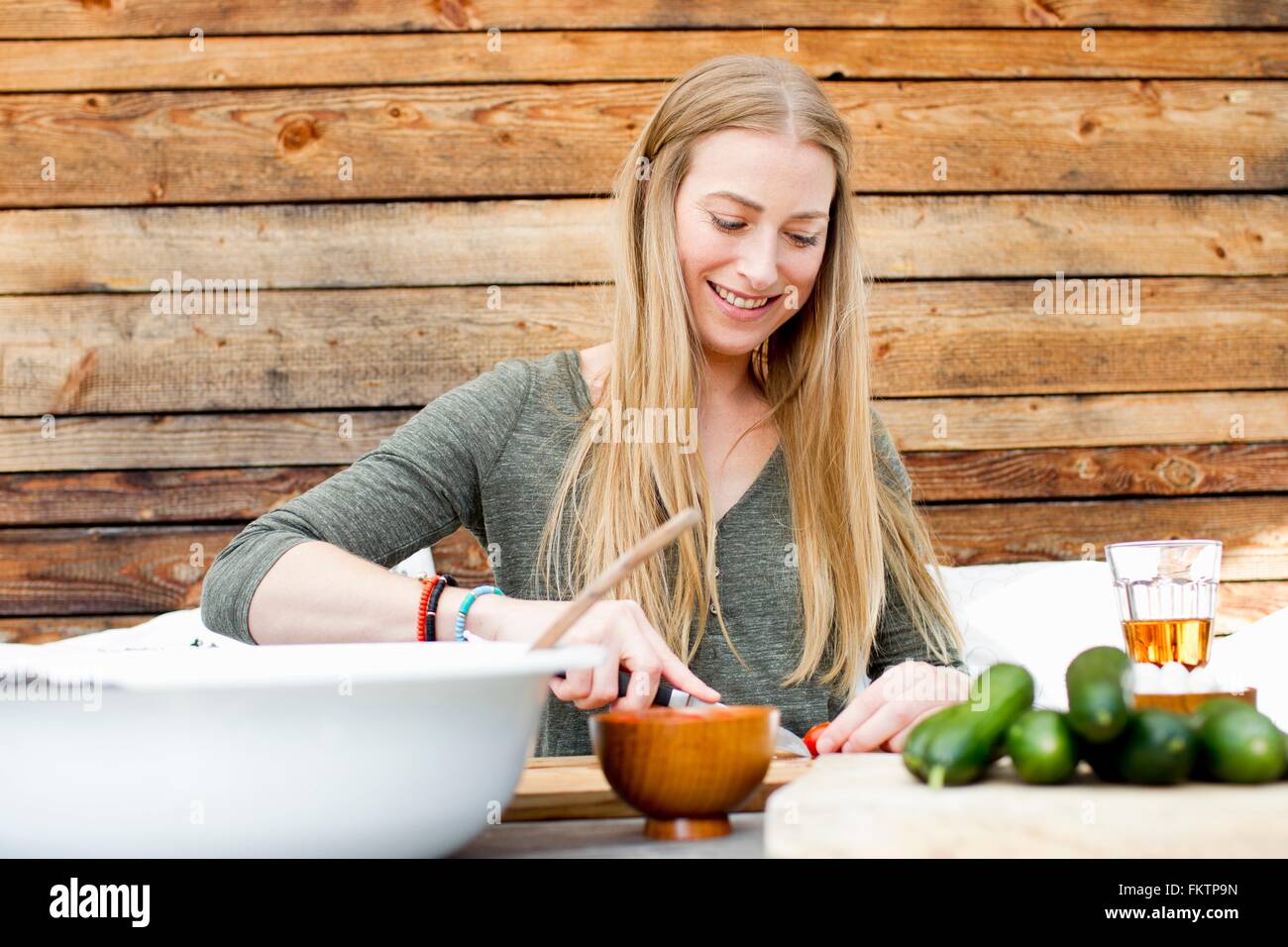 Mid adult woman preparing food at table outdoors Stock Photo