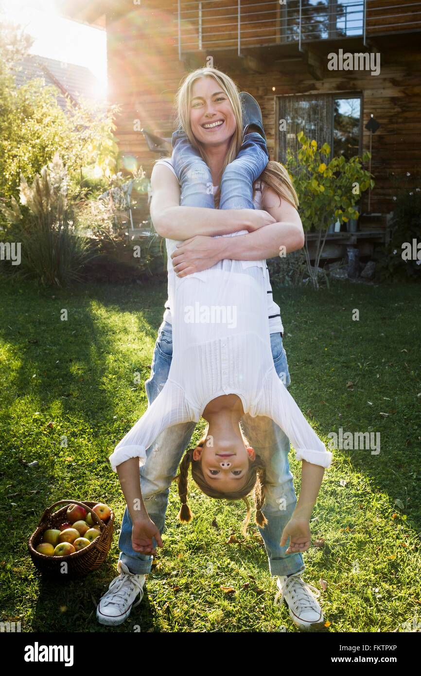 Mother lifting daughter upside down in garden Stock Photo