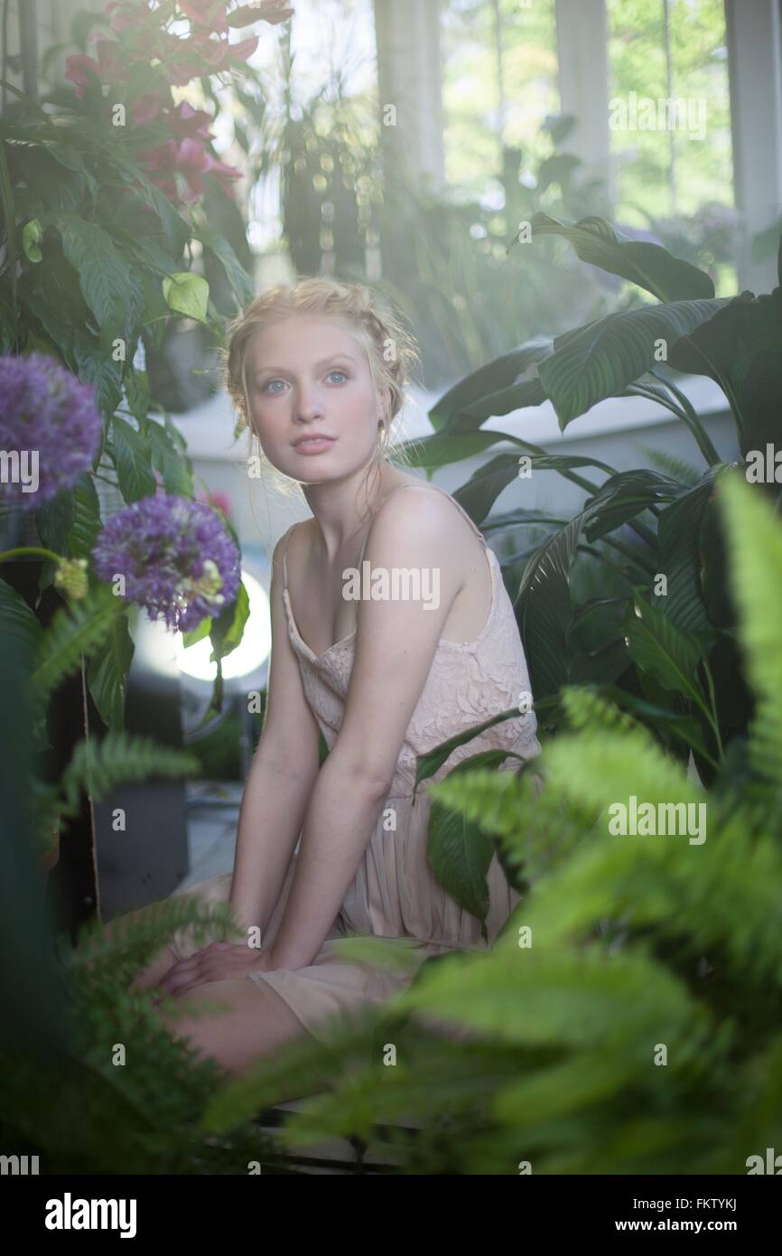 Portrait of young woman sitting in room full of plants Stock Photo - Alamy