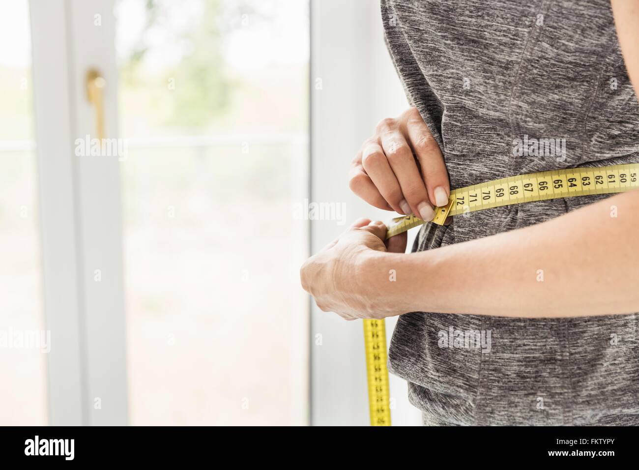 Cropped shot of mature woman measuring her waist Stock Photo